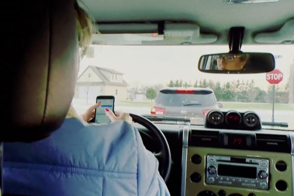 a woman texting as seen from the back seat of a car