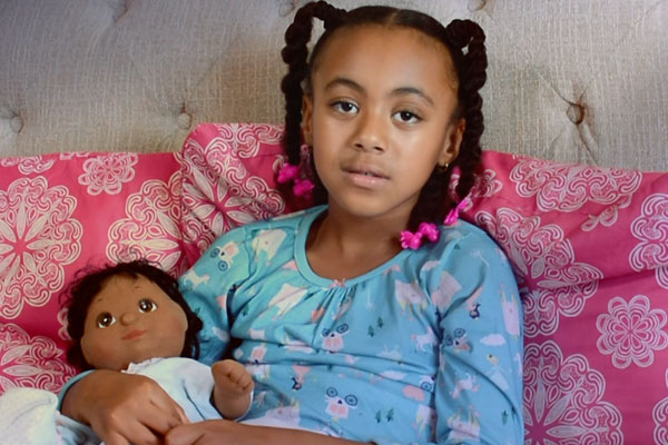 little girl looking at the camera with a doll