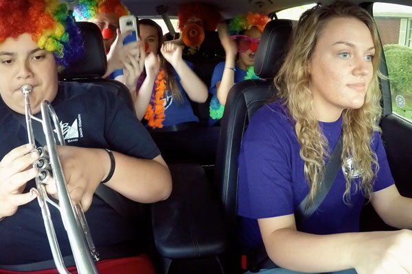 a teen driving a car full of clowns making a lot of noise