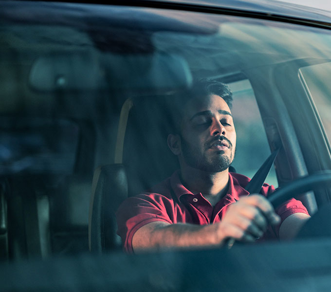 man falling asleep at the wheel of a car