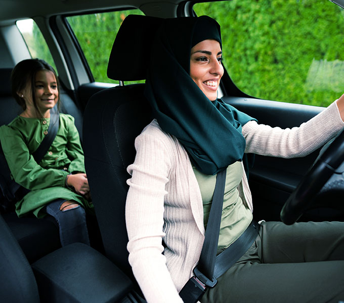 musilm woman driving with her child in a car both wearing seatbelts