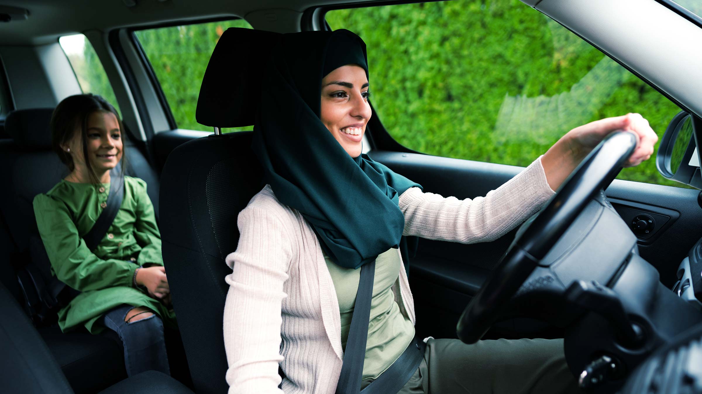 musilm woman driving with her child in a car both wearing seatbelts