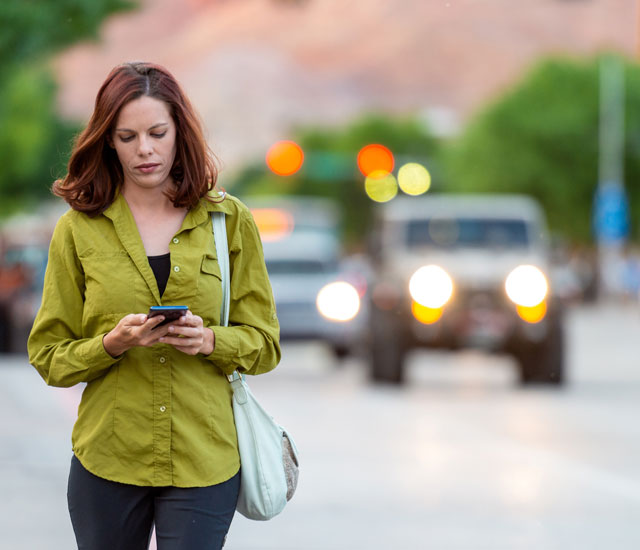 red headed woman walking and looking on her phone