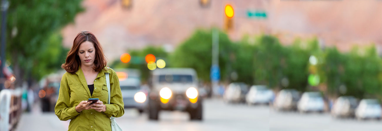 red headed woman walking and looking on her phone