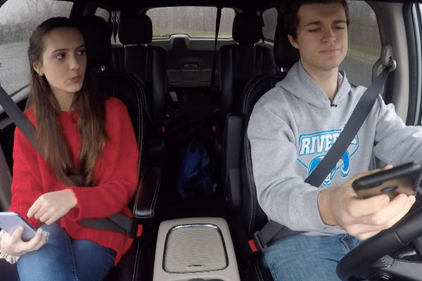 two teens in a car with the driving texting