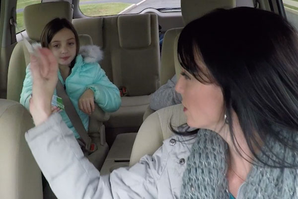 a mom driving a looking into the backseat at her daughter