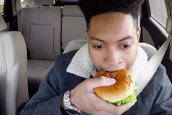 close-up of a guy eating a sandwich while driving