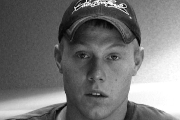 a black a white photo of a teen wearing a baseball cap