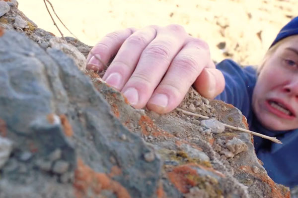 girl rock climbing and holding on